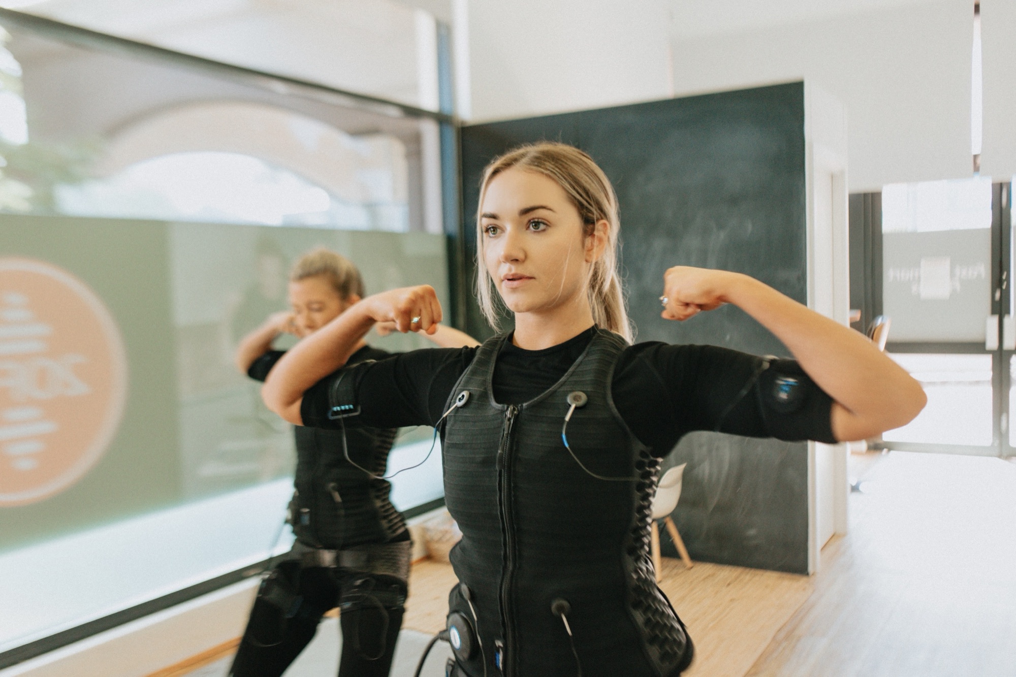 Woman in a boxing guard stance wearing an EMS training suit at 20FIT