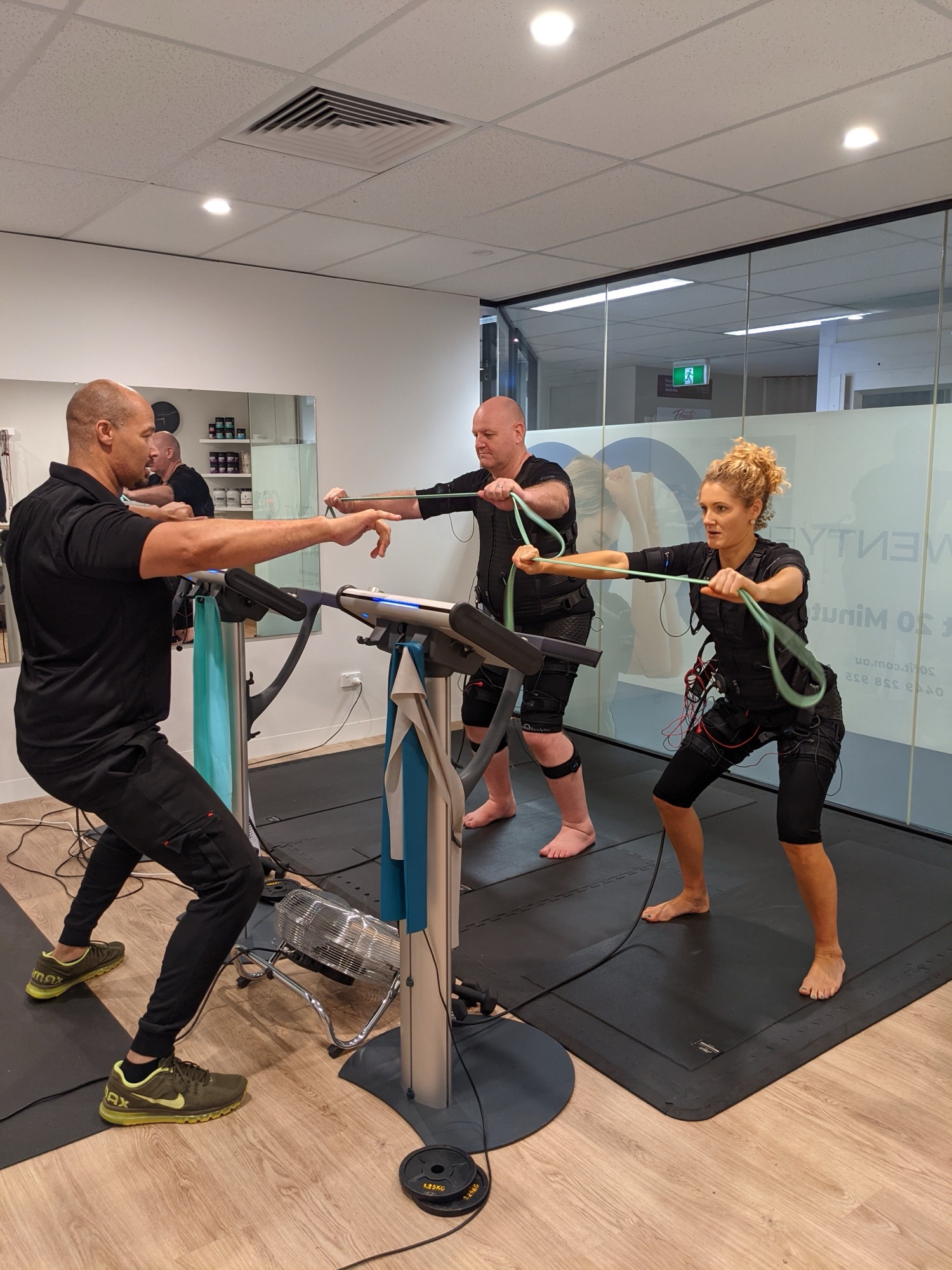 Coach running a resistance band row with clients